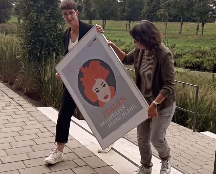 Veranstalterinnen bringen Poster "Frauen im geteilten Deutschland" kommt an seinen Platz